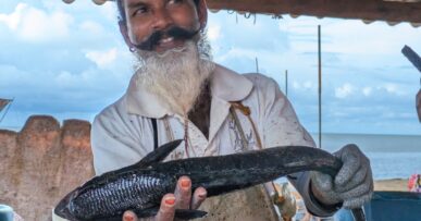 Fisherman holding a fish and showing its underbelly, Negombo, Sri Lanka.